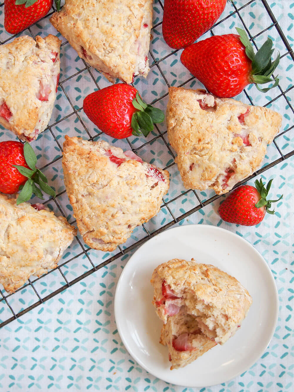 These strawberry scones are made with mascarpone and a double doze of strawberries for a wonderfully soft, fruity mouthful in every bite. Easy to make, they're a wonderful snack. strawberry scones with mascarpone on cooling rack with strawberries between them
