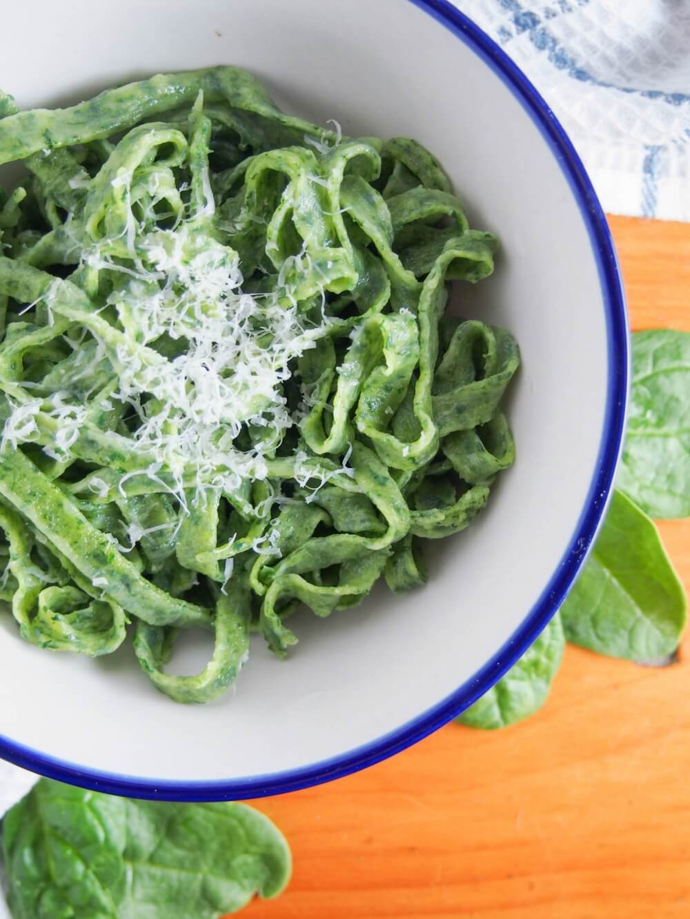 bowl of fresh spinach pasta topped with a little parmesan