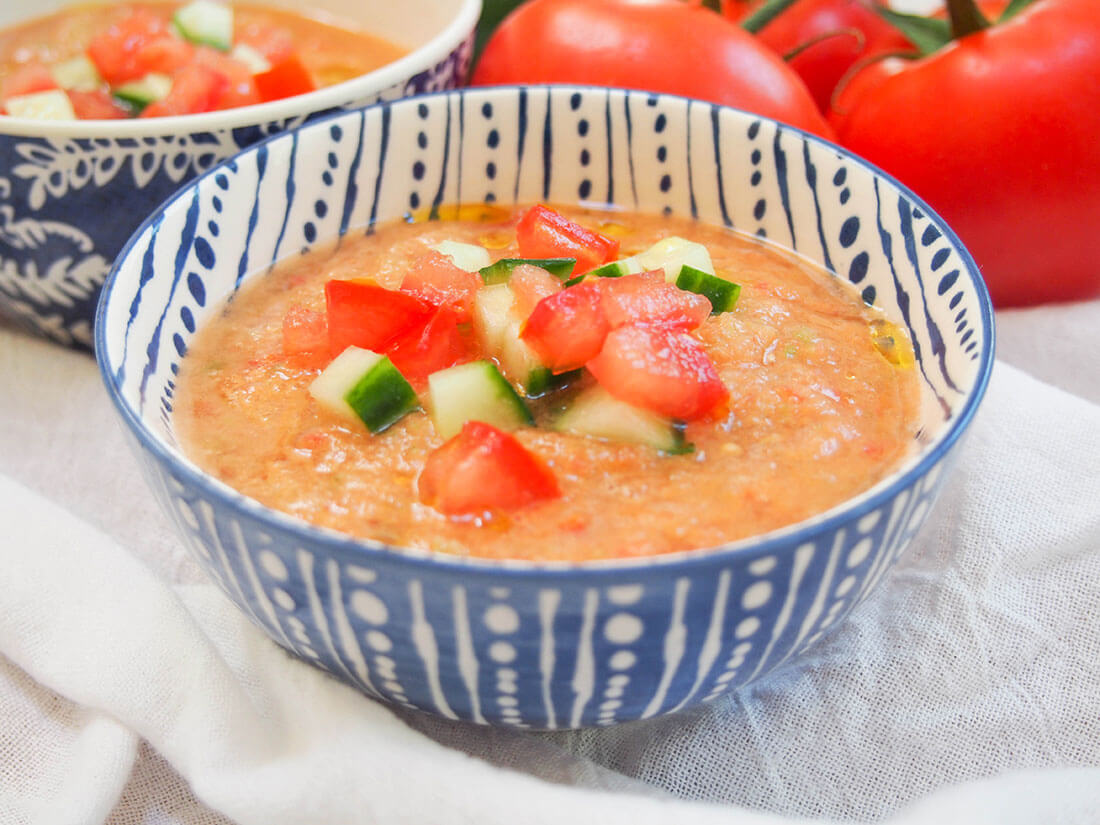 bowl of gazpacho garnished with tomato and cucumber