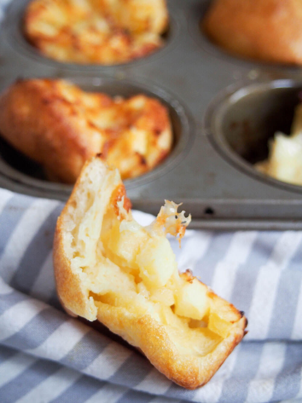 torn apple and cheddar cheese Yorkshire pudding showing inside in front of pan