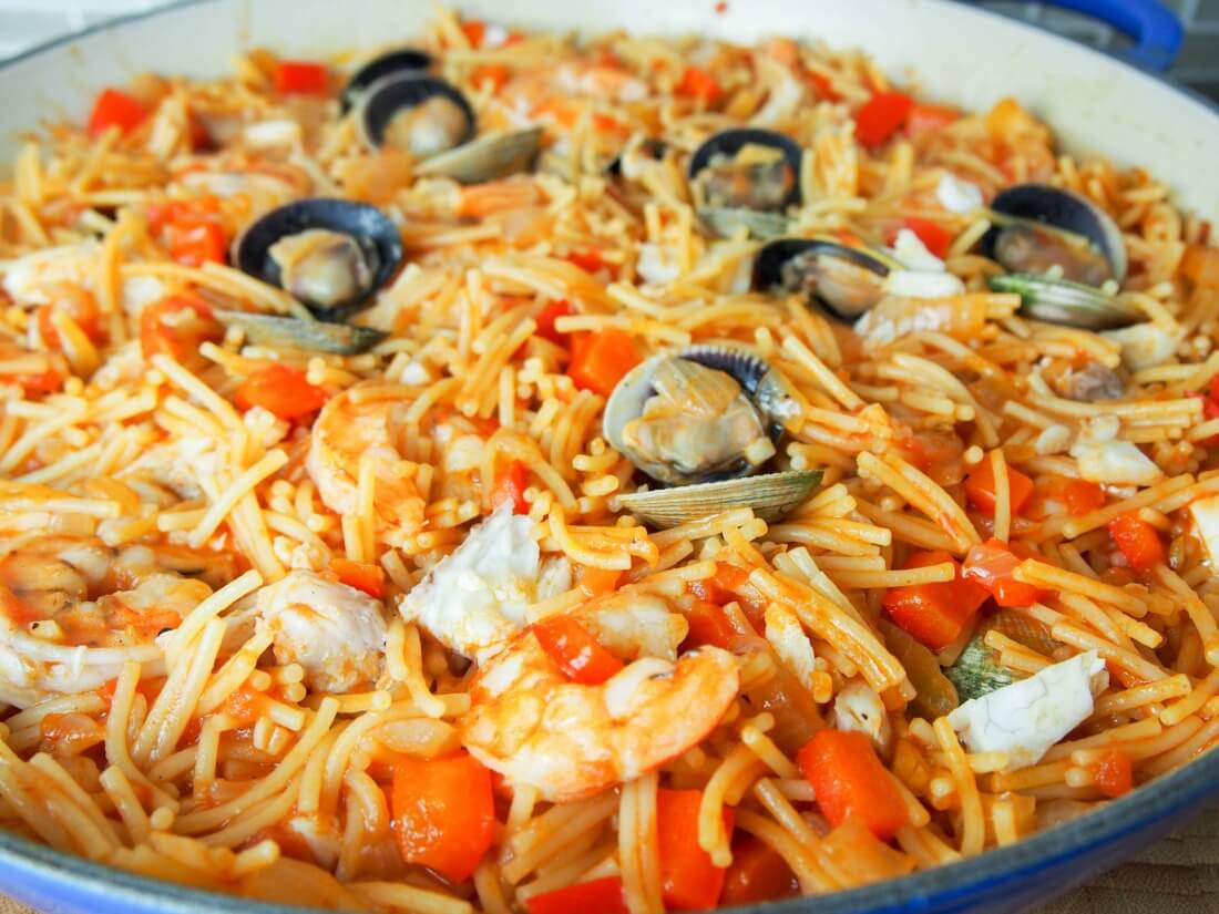 fideua (Catalan pasta paella) in pan close up showing clams on top