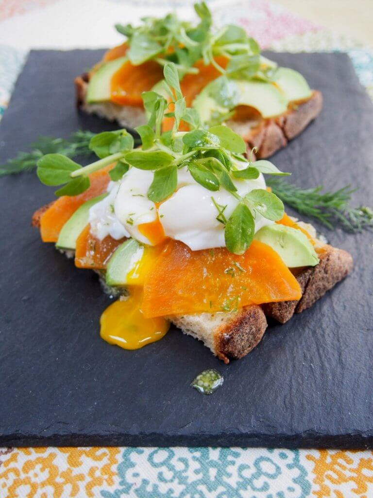 Golden beet and avocado toast with lemon-dill dressing with oozing egg on top