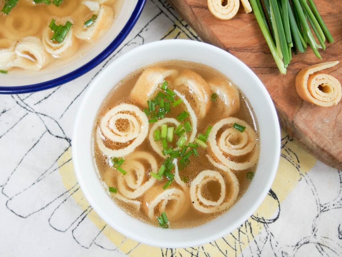 bowl of German pancake soup viewed form overhead with coils of pancake and chives to side