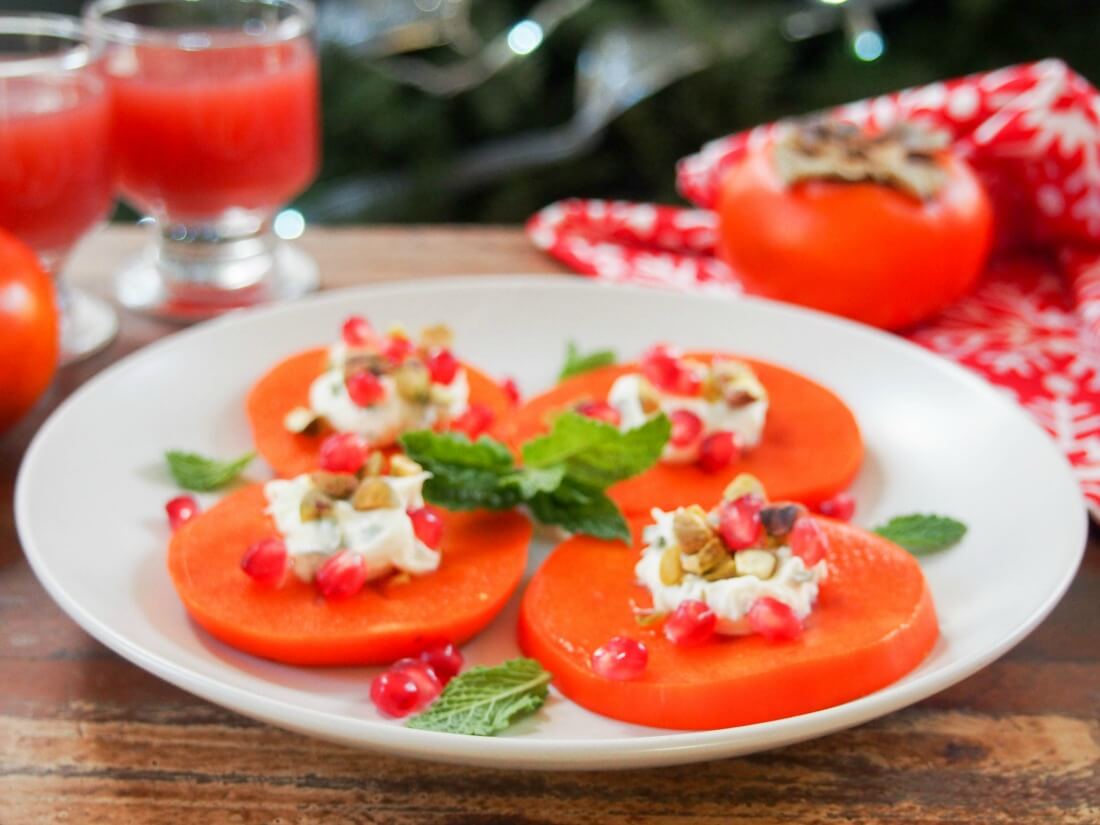 plate of easy persimmon appetizer with minted mascarpone with a persimmon and glasses behind