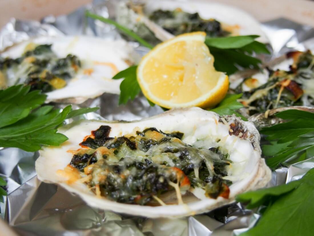 close up of oysters Rockefeller with lemon slice behind