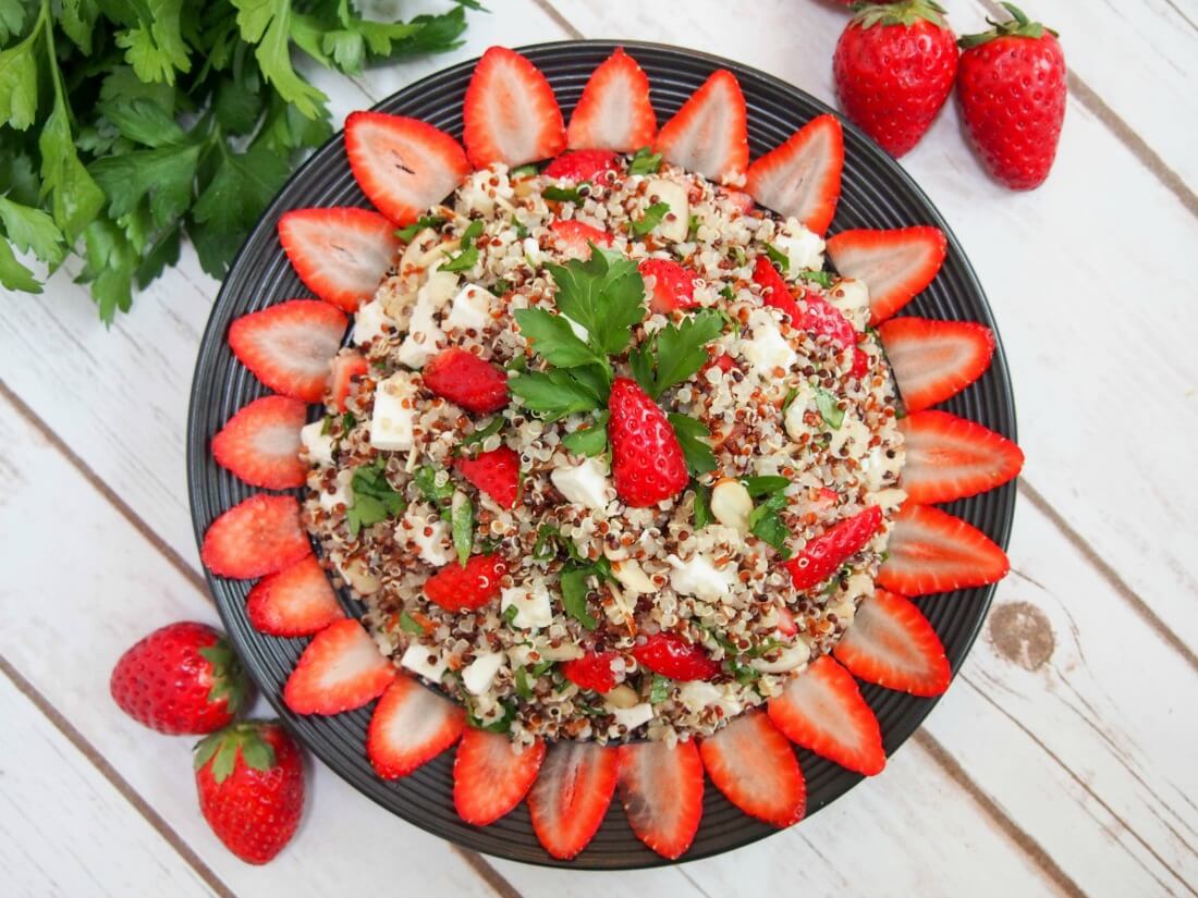 strawberry quinoa salad with feta on plate with strawberry slices around edge as decoration viewed from above