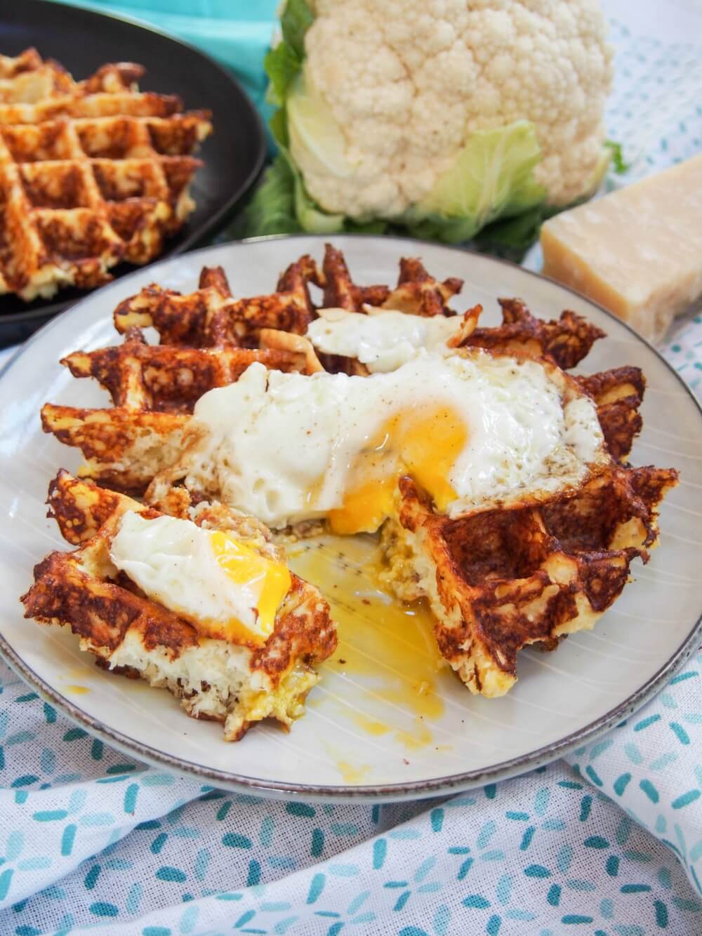Cauliflower waffle with egg on top and quarter cut out from it