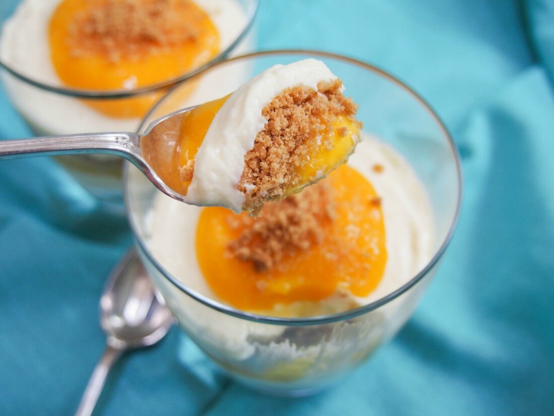mango cheesecake parfait with spoonful held over glass