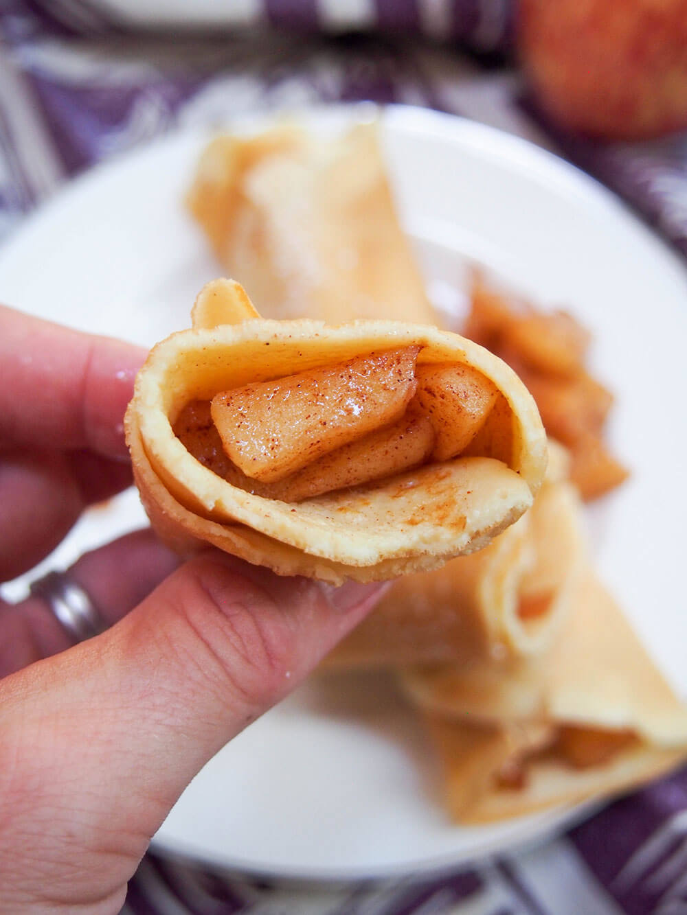 apple crepes held in hand showing filling inside