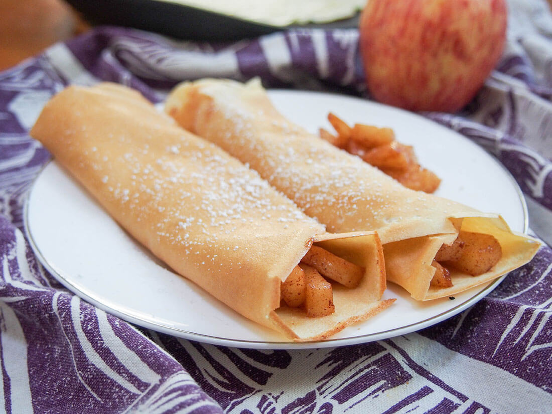 apple crepes on plate with apple behind