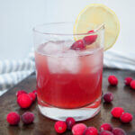 cranberry whiskey sour in glass with lemon garnish
