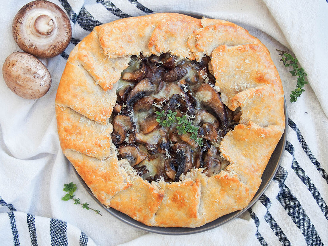 mushroom galette viewed from overhead with fresh mushrooms to side