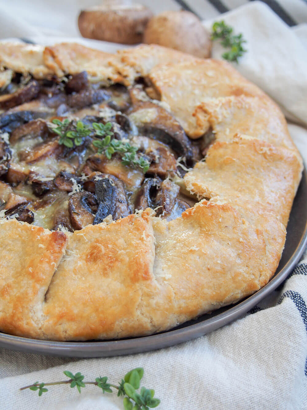 side view of mushroom galette showing golden pastry around edge with thyme garnish on top