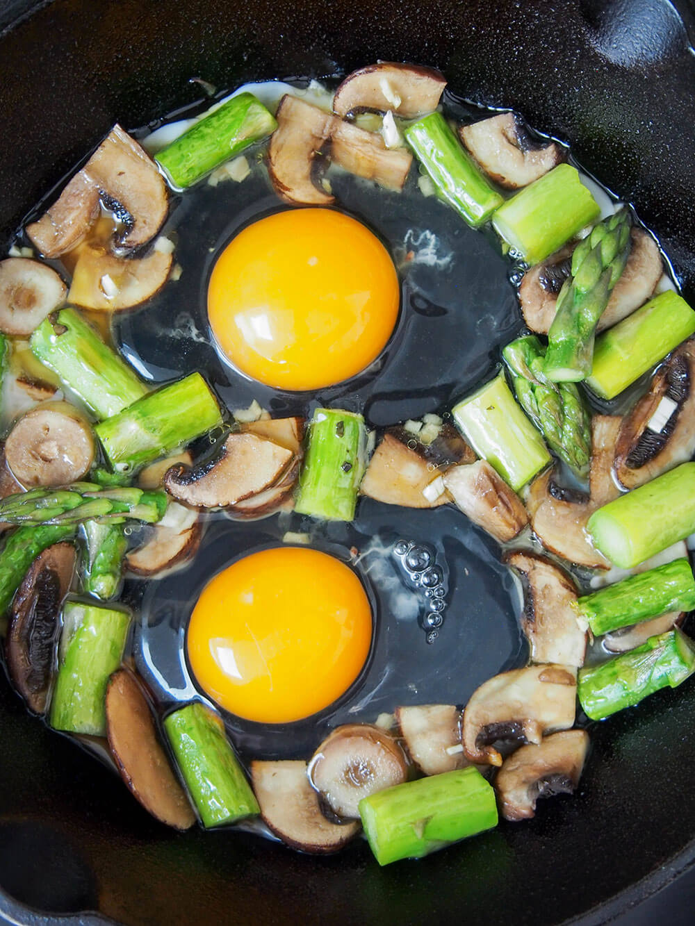 adding eggs to vegetables for Baked eggs with mushrooms and asparagus
