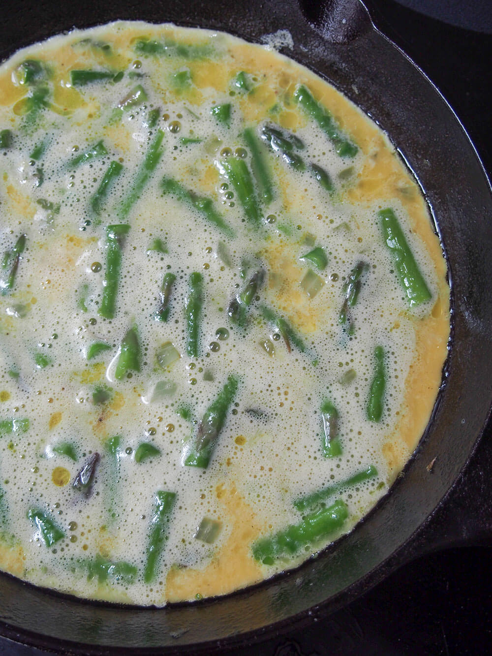 eggs added to asparagus to make frittata