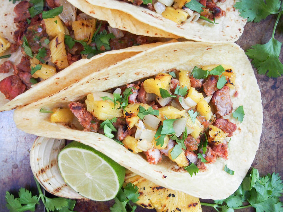 tacos al pastor topped with pineapple