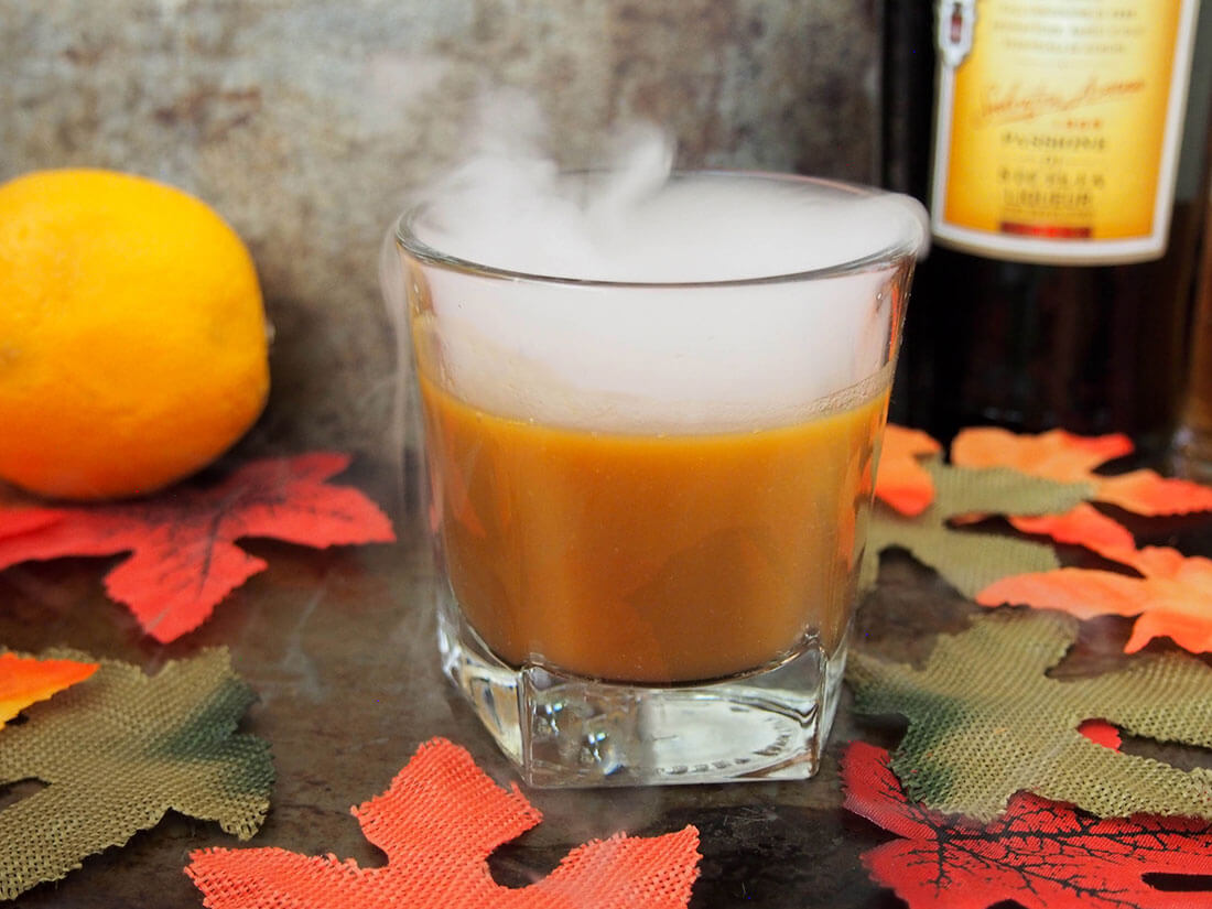 faller for appelsin: amaro gresskar cocktail med flaske og appelsin bak