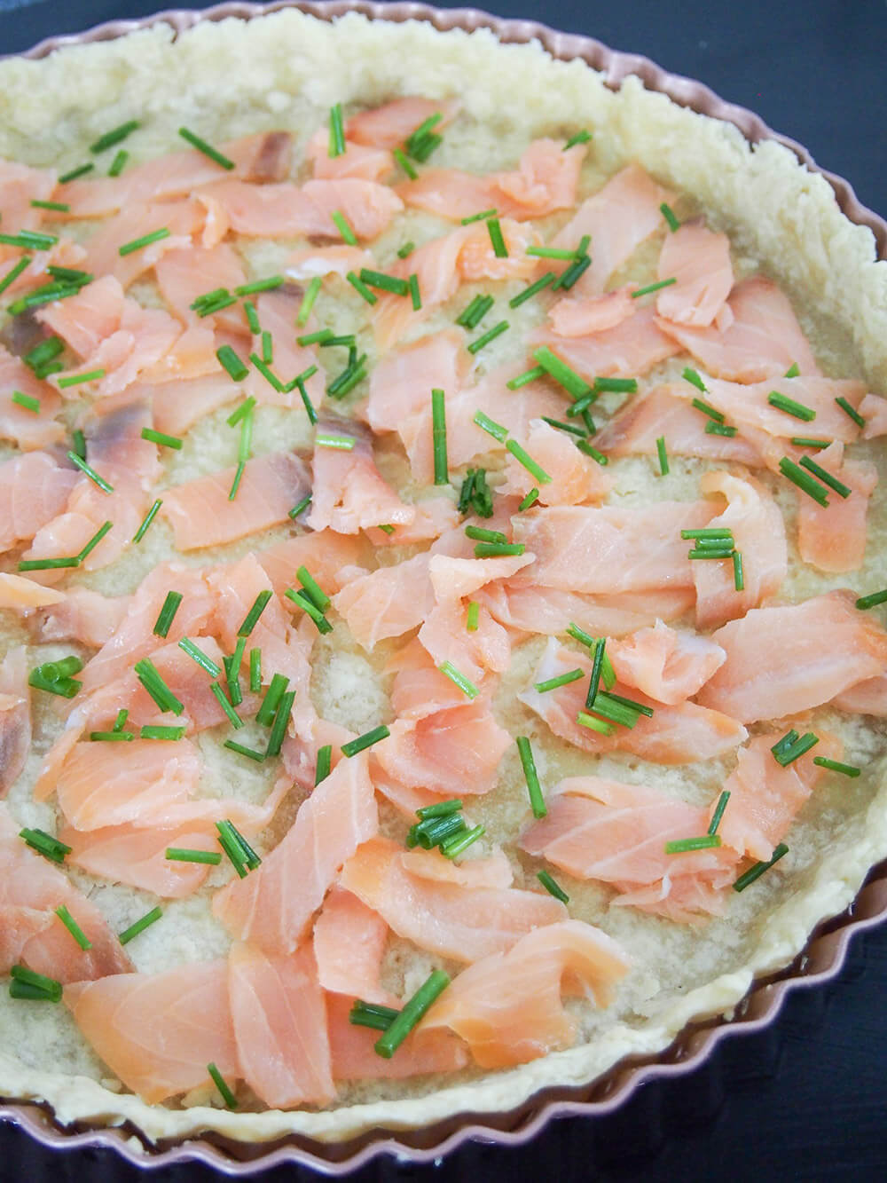 adding smoked salmon filling to base for smoked salmon quiche
