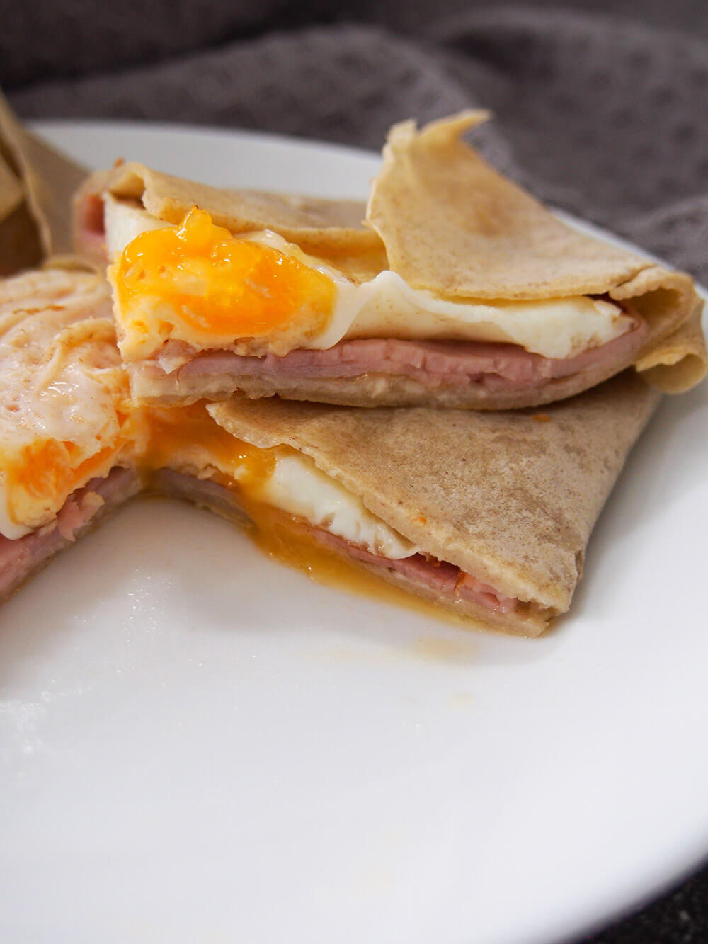 buckwheat crepes cut open to show cheese, ham and egg filling