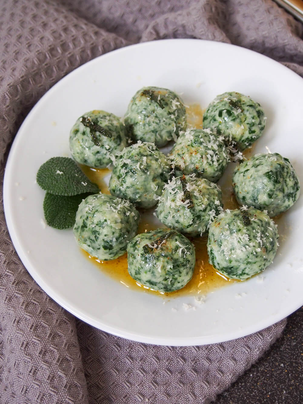 Ricotta and spinach gnudi topped with parmesan and with sage leaf garnish