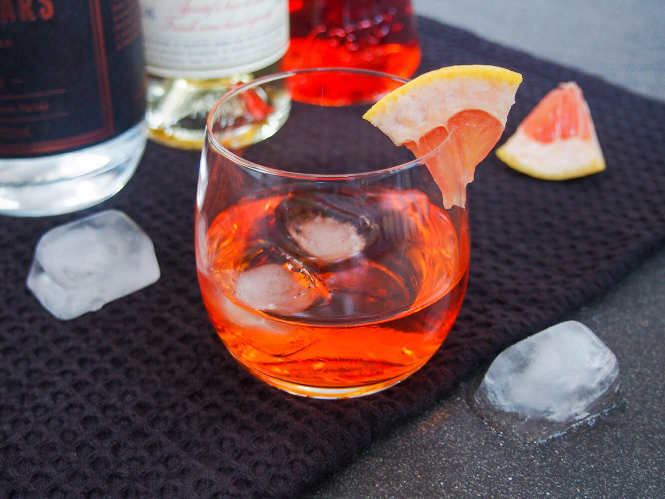 glass of unusual negroni with bottles behind
