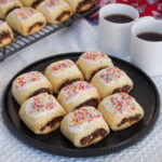 plate of cucidati cookies with coffee cups to side