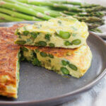 slice of asparagus frittata on top of rest on plate