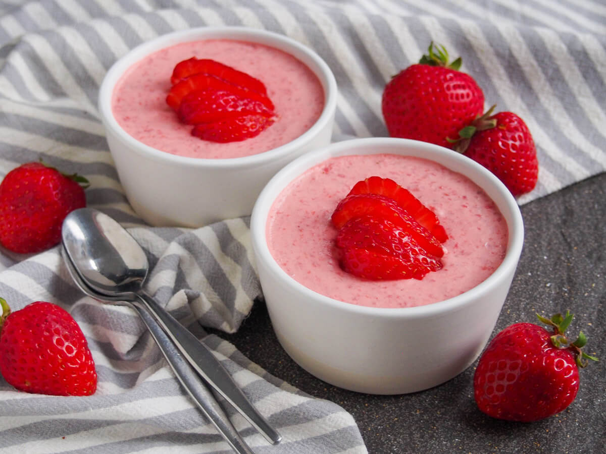 two dishes with easy strawberry mousse with spoons to side and strawberries to side