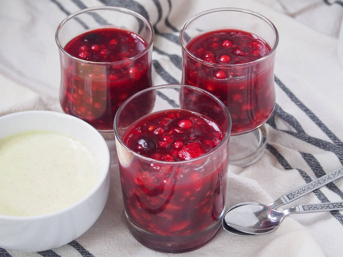 Three glasses of Rote Grütze (Rote Gruetze) with a bowl of vanilla sauce to the side