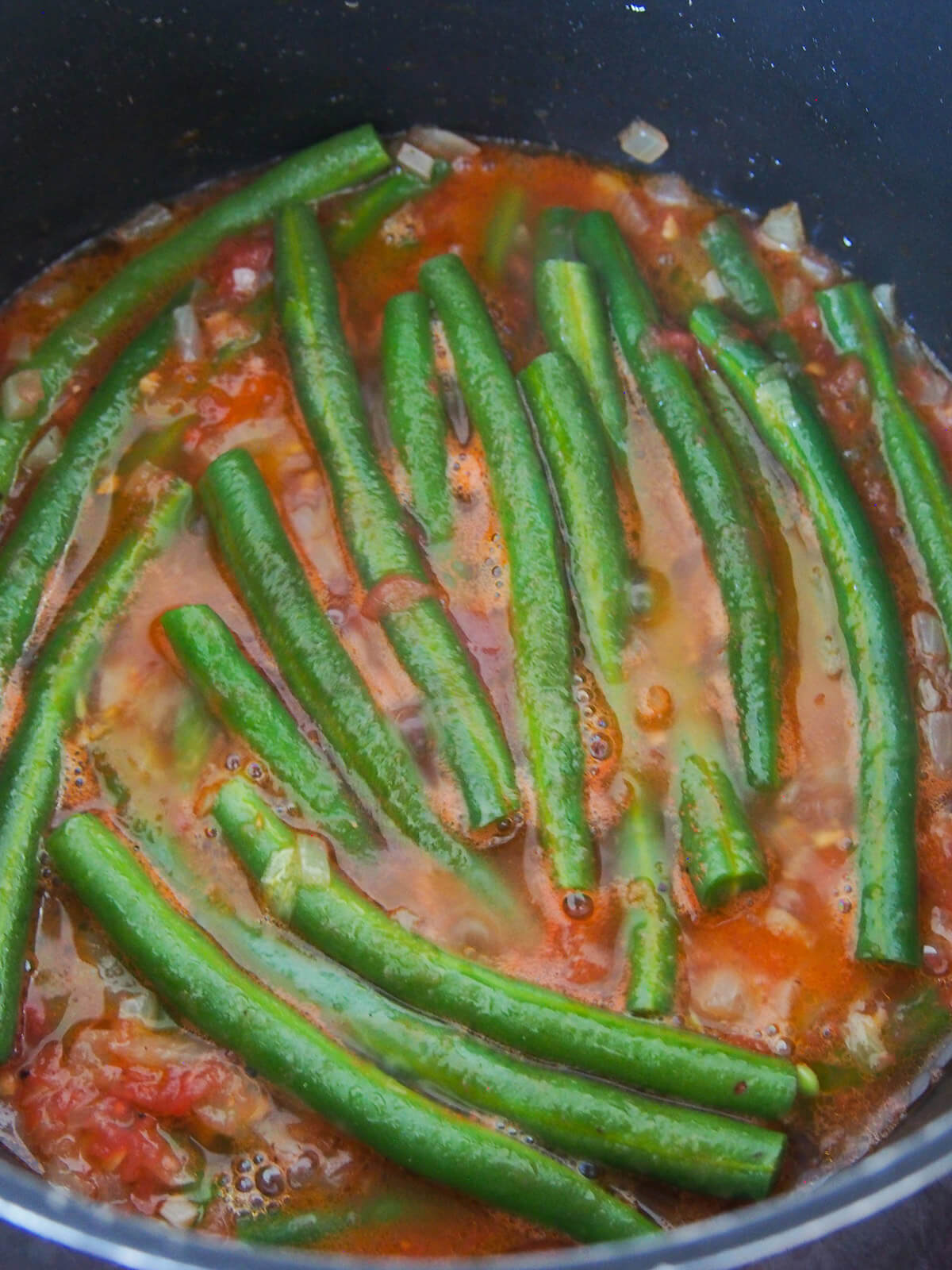 green beans simmering in tomato-oil sauce
