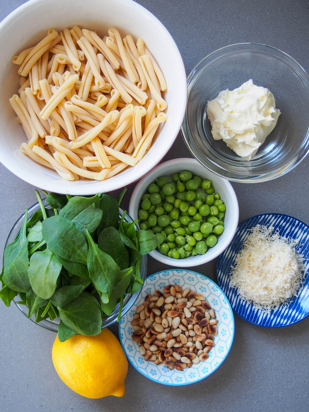 bowls of pasta, mascarpone, peas, spinach, parmesan, pine nuts and a lemon