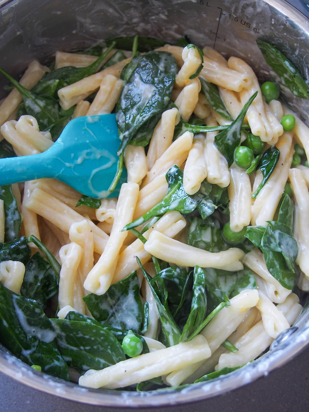 mixing spinach and sauce into pasta