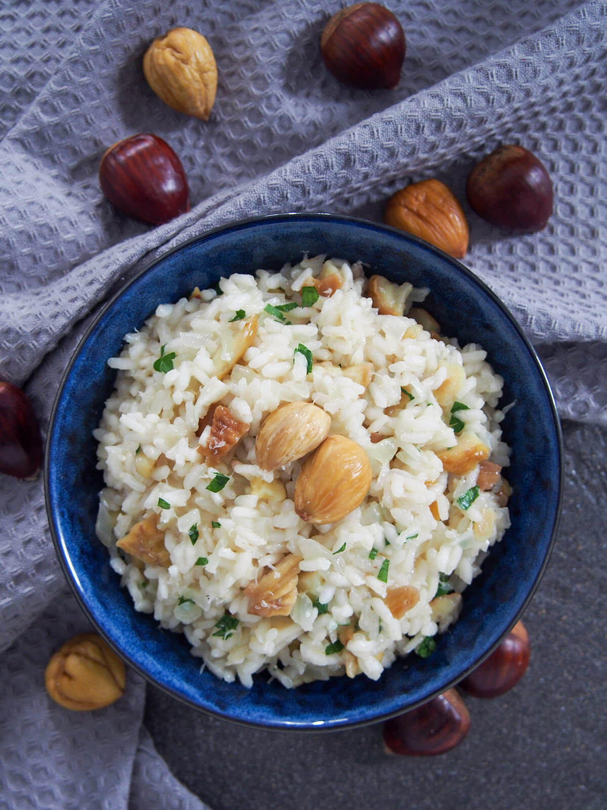 bowl of chestnut risotto from overhead with whole chestnuts around bowl