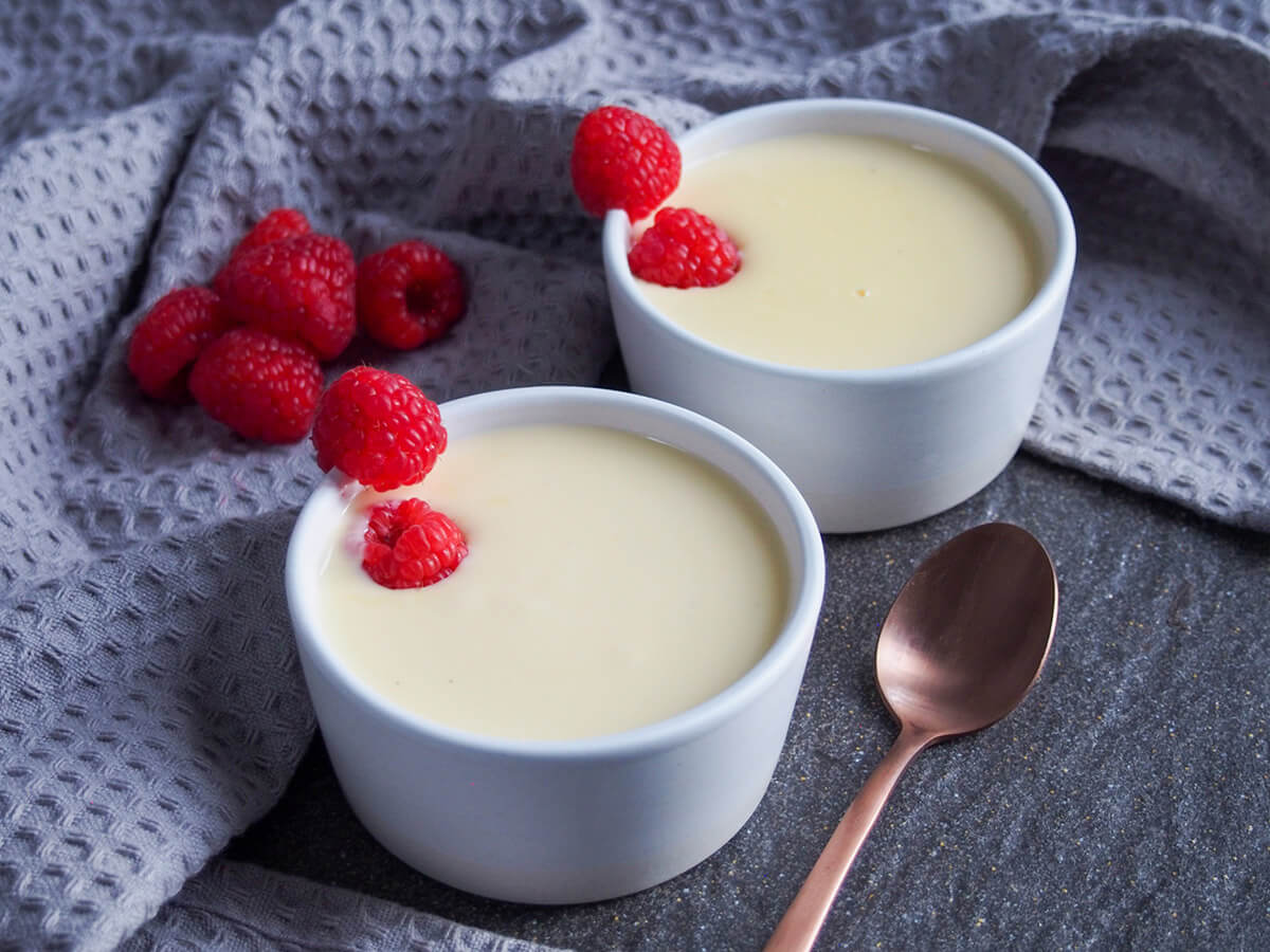 two bowls of creme Anglaise with raspberries as decoration on bowls and to side