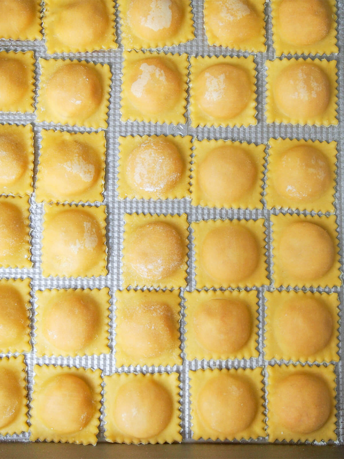 rows of ravioli on baking sheet before cooking
