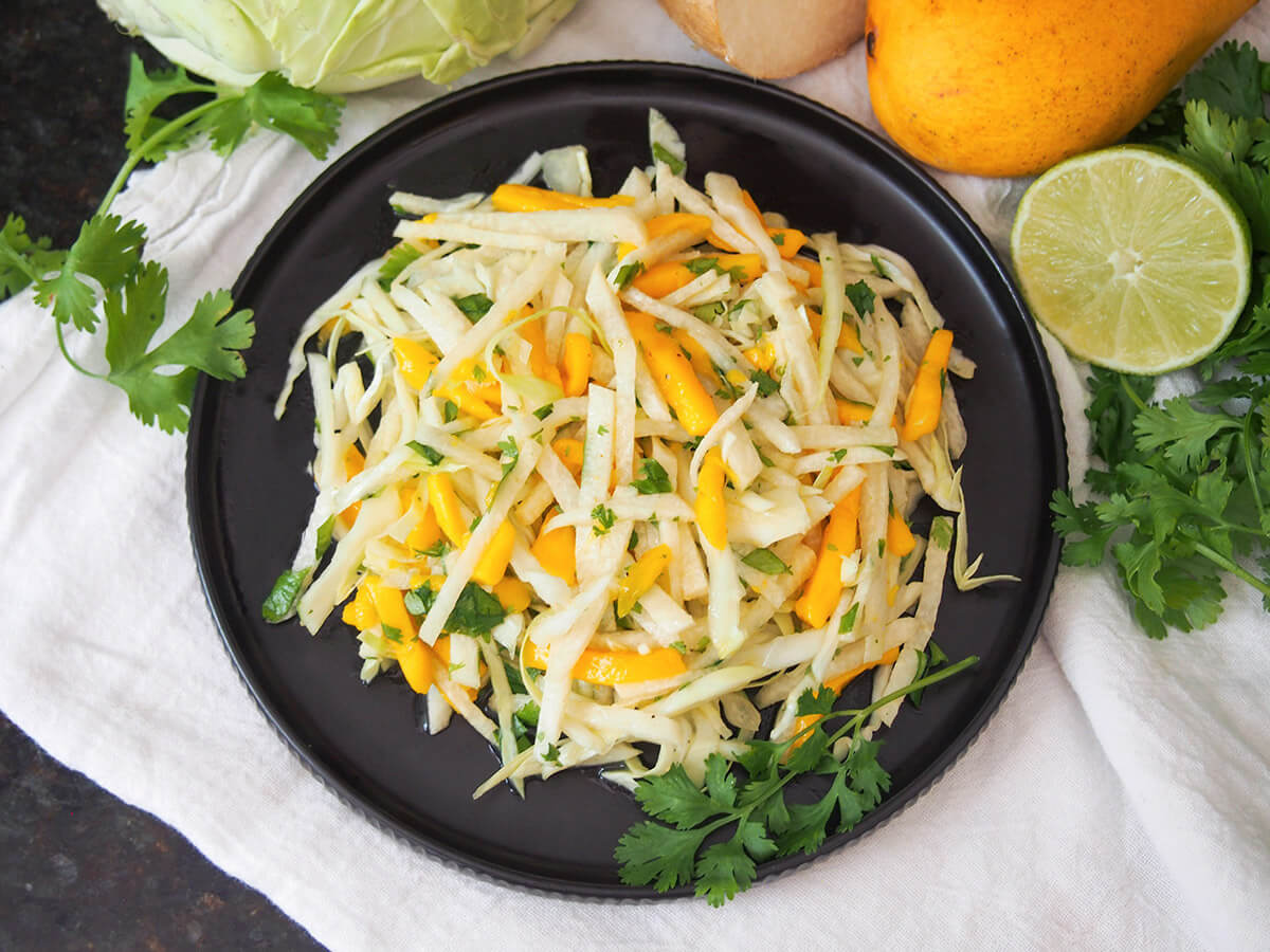 plate of mango jicama slaw from overhead with cilantro, lime and other ingredients to side