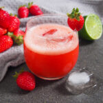 glass of strawberry agua fresca with strawberries to side