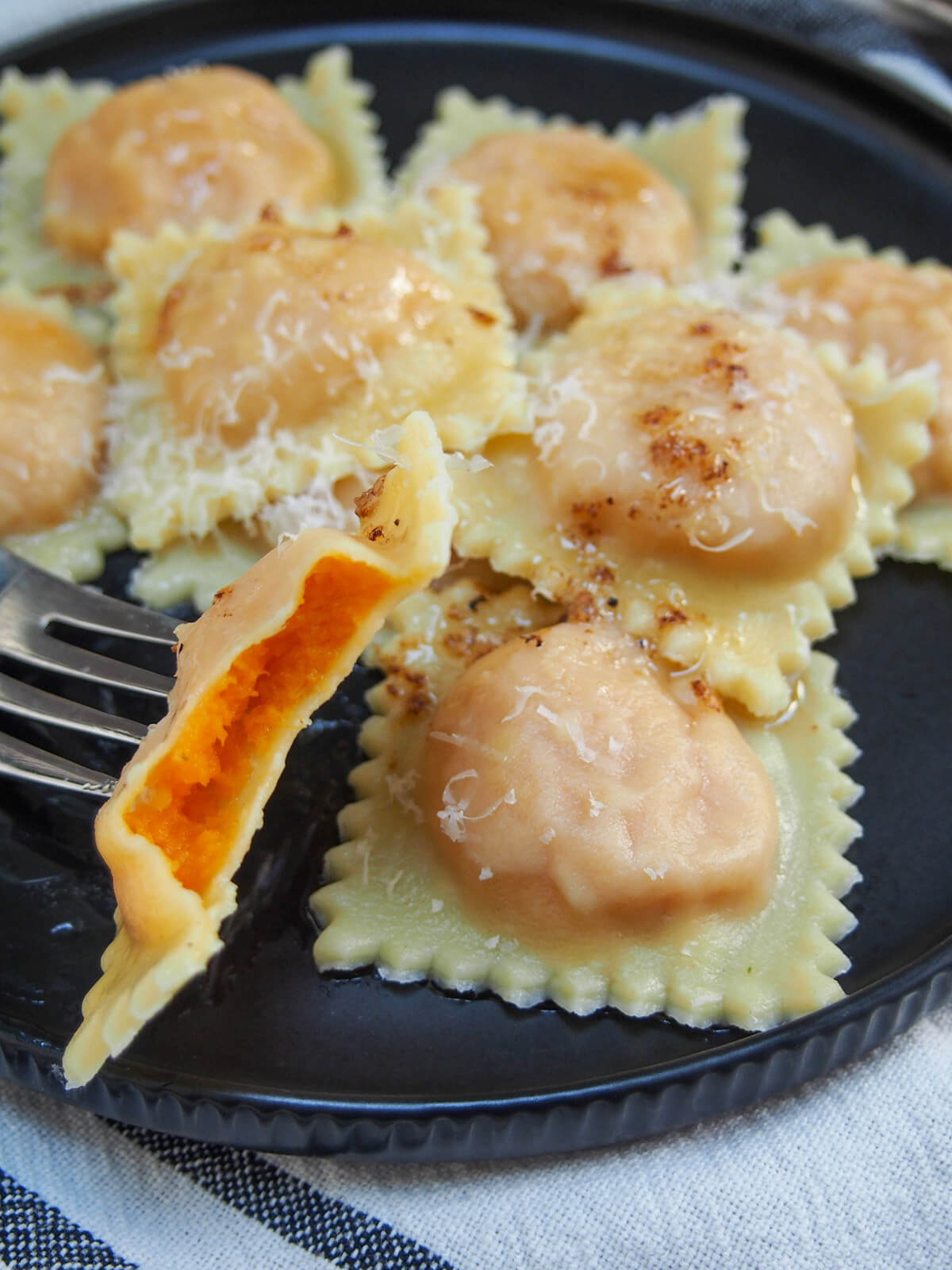 plate of sweet potato ravioli with one bitten into showing filling on fork at front