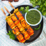 plate of paneer tikka with cilantro mint chutney in side