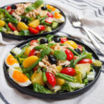 plate of salade Nicoise with second plate of salad behind
