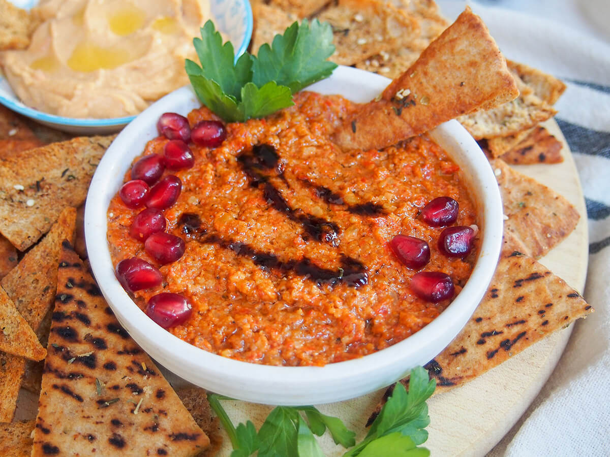 dish with muhammara pepper walnut dip surrounded by pita chips