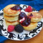 plate with syrniki Russian cheese pancakes topped with jam and cream