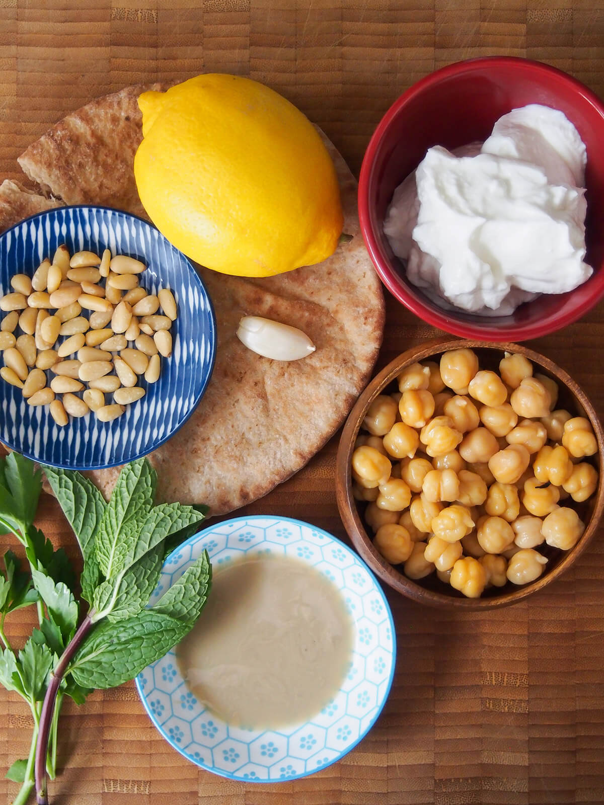 bowls with chickpeas, yogurt, pine nuts, tahini with lemon and pita bread