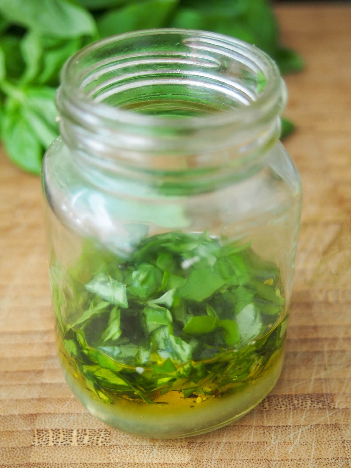 jar with ingredients to make basil dressing before mixing with herbs sitting on top