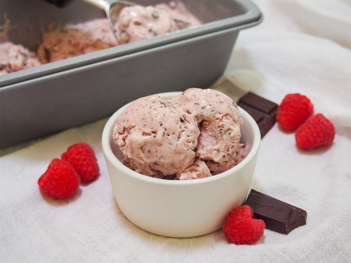 no churn raspberry chocolate chip ice cream in dish with container with more behind