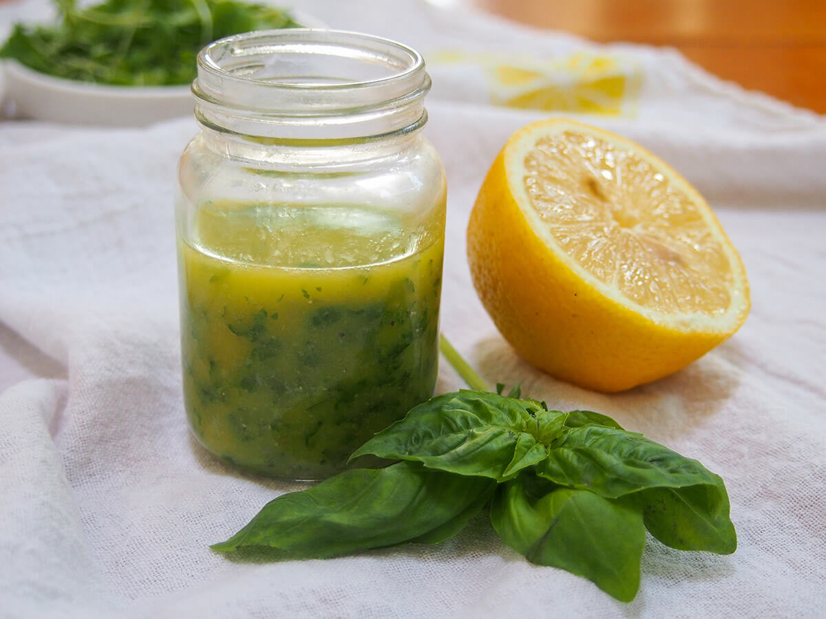 jar of lemon basil vinaigrette with half lemon and sprig of basil to side