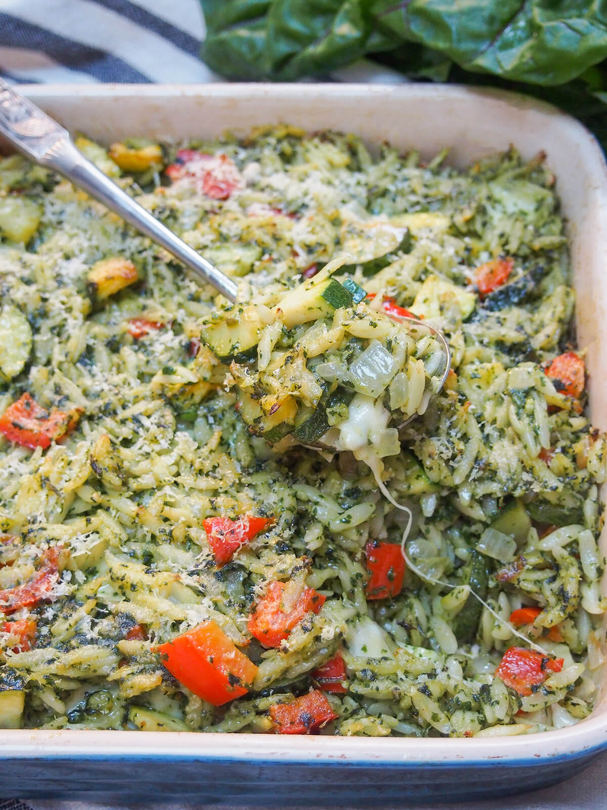 creamy chard pesto baked orzo with spoonful sitting on top and cheese pull