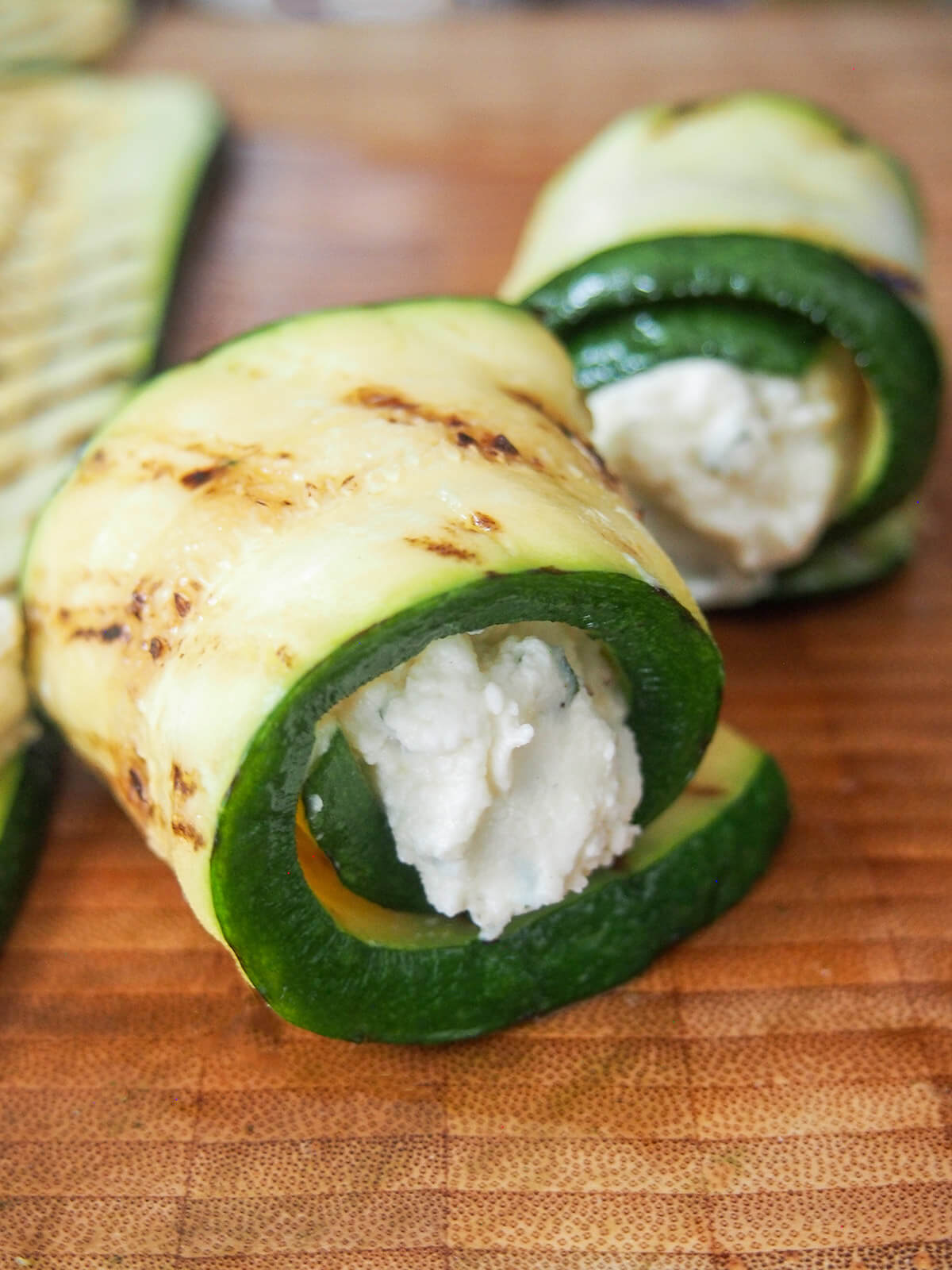 a rolled up piece of zucchini with cheese filling and other roll behind