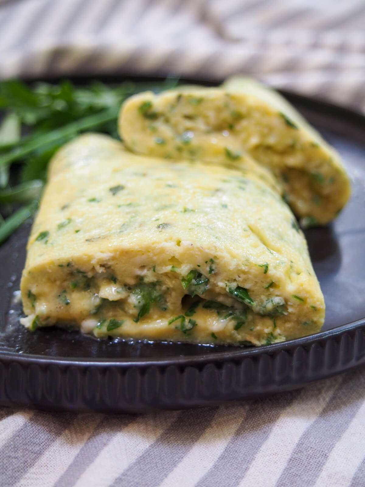 cut open French omelette with herbs from side showing soft inside