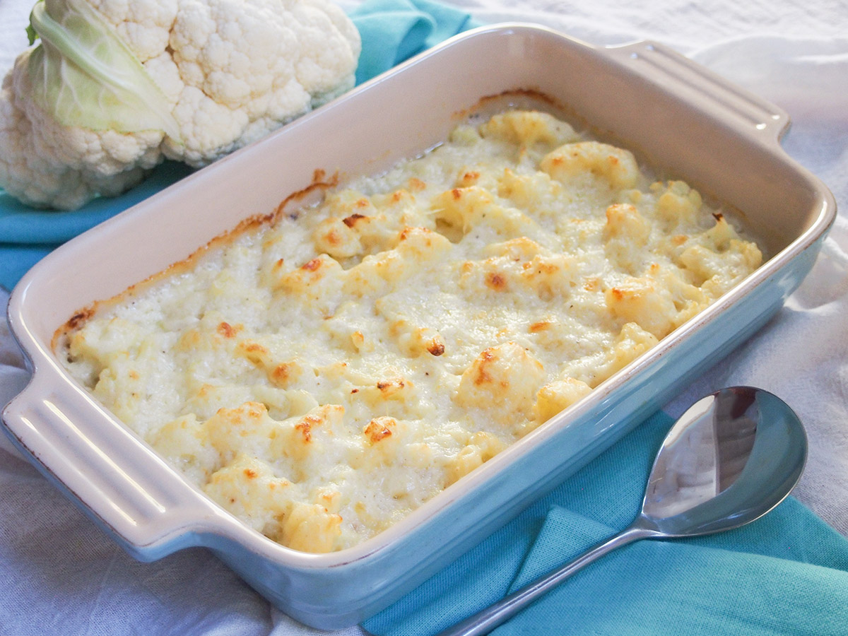 dish of cauliflower cheese with serving spoon in front